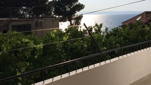A balcony with a view of the sea and a building in the background. - Apartment in Podgora with Seaview, Terrace, Air condition, WIFI (4492-3) (Podgora)