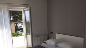 A bedroom with a bed, a window, and a view of greenery outside. - Apartment in Podgora with Seaview, Terrace, Air condition, WIFI (4492-3) (Podgora)