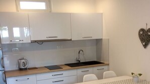 Une cuisine moderne avec des meubles blancs, un plan de travail en bois et un coin repas comprenant une table et des chaises blanches.