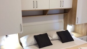 Une chambre à coucher comprenant un lit, deux tables de chevet, une commode et une armoire.