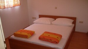 A single bed with a wooden headboard, two white pillows, and two orange blankets. - Apartment in Omiš with Balcony, Air condition, WIFI, Washing machine (3422-4) (Omiš)