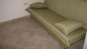 A green sofa with two cushions in a room with beige tiled flooring and white walls. - Apartment in Omiš with Balcony, Air condition, WIFI, Washing machine (3422-4) (Omiš)