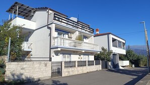 Une maison moderne à deux étages, dotée d’un balcon, d’un garage et d’un mur en pierre.