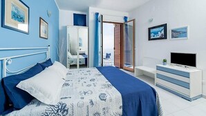 Ein Schlafzimmer mit Bett, Kommode, Fernseher und Balkon mit Blick.