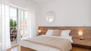Ett sovrum med en stor säng, två sänglampor, en rund spegel och en skjutdörr i glas som leder ut till ett utomhusområde.