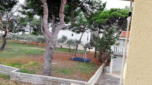 A residential area with a grassy yard, a swing set, and a white building in the background. - Apartment in Vir with Terrace, Air condition, WIFI (4594-1) (Vir)