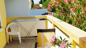 A small outdoor patio with a table set for two, featuring a tablecloth with a nautical theme, two wicker chairs, and a potted plant with pink flowers. - Apartment in Vir with Terrace, Air condition, WIFI (4594-1) (Vir)
