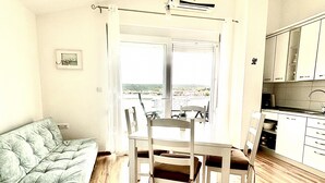 Una sala de estar con sofá, mesa de comedor, sillas y vistas por una ventana.