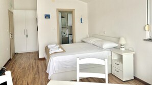 Una habitación pequeña y limpia con cama, mesita de noche, una silla y un armario.