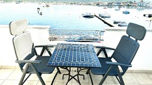 Una terraza con una mesa y dos sillas que da a un puerto deportivo con barcos.