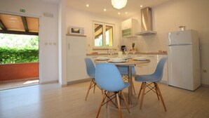 A modern kitchen with a dining table set for four, light-colored cabinets, and a stainless steel refrigerator. - Holiday Home in Poreč with Terrace, Air condition, WIFI, Dishwasher (4400-4) (Porec)
