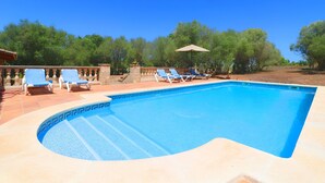 A rectangular swimming pool with a blue mosaic border, surrounded by a tiled deck.