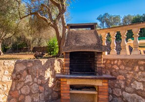 Estrutura de forno a lenha ao ar livre, com parede de pedra e balaustrada decorativa.