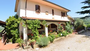 A two-story house with a tiled roof, arched windows, and a covered porch with potted plants and flowers. - Vacation Home in Nievole with 2 bedrooms sleeps 4 (Nievole)