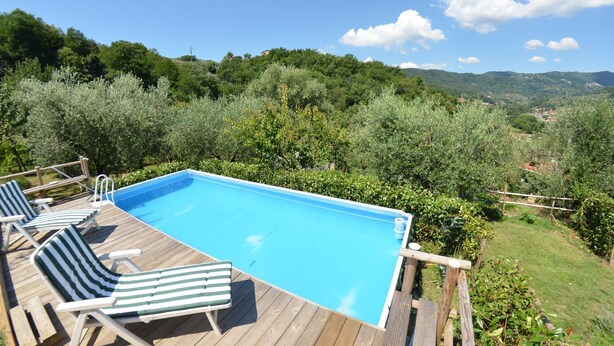 A wooden deck with a swimming pool, lounge chairs, and a view of a lush landscape with trees and hills. - Vacation Home in Nievole with 2 bedrooms sleeps 4 (Nievole)