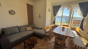 A living room with a sofa, wooden table, and chairs, a clock on the wall, and a view of the sea through large windows. - Apartment in Seline with Seaview, WIFI, Washing machine (4209-1) (Seline)