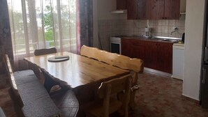 A dining area with a wooden table and benches, a kitchen with wooden cabinets, a stove, and a coffee maker. - Apartment in Seline with Seaview, WIFI, Washing machine (4209-1) (Seline)