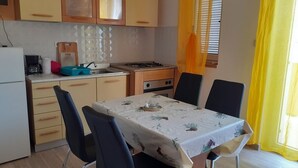 Una cocina compacta con una mesa de comedor, sillas y un refrigerador.