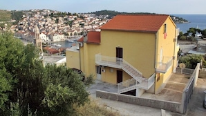 Un bâtiment jaune avec un toit rouge, un balcon et une vue sur une ville côtière.