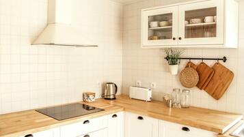 Eine Küche mit weißen Schränken, einer Holzauskładung, einem Toaster, einem Wasserkocher und hängenden Küchenutensilien.