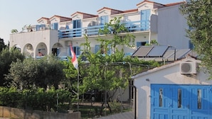 A building with a white facade, blue shutters, and a flag. - Apartment in Sućuraj with Seaview, Balcony, Air condition, WIFI (3560-1) (Sucuraj)