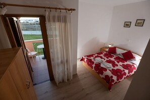 A bedroom with a bed, a nightstand, a chair, and a view of the outside. - Apartment in Privlaka with Seaview, Balcony, Air condition, WIFI (3598-2) (Privlaka)