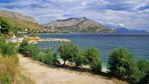 A coastal road with a clear view of the sea, a rocky mountain, and a small settlement with houses. - Studio apartment in Duće with Seaview, Balcony, Air condition, WIFI (4173-1) (Duce)
