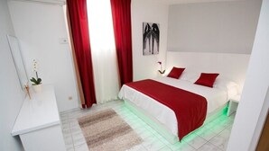 Un dormitorio moderno con cama, cortinas rojas, una mesita de noche blanca y una planta pequeña.