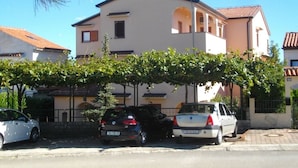 A two-story building with a flat roof and a balcony. There are three cars parked in front of the building. - Studio apartment in Poreč with Terrace, WIFI (3794-1) (Porec)