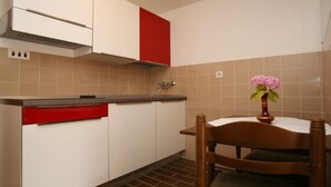 A compact kitchen with white and red cabinets, a wooden chair, and a vase of flowers on the table. - Studio apartment in Poreč with Terrace, WIFI (3794-1) (Porec)