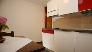 A kitchen with white cabinets, a red lower cabinet, and a tiled backsplash. - Studio apartment in Poreč with Terrace, WIFI (3794-1) (Porec)