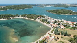 Vista aérea de un pueblo costero con puerto deportivo, playa y zonas residenciales.