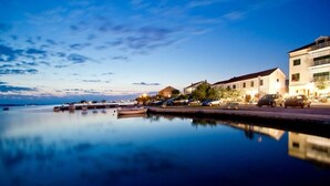 A waterfront property with a dock, boats, and buildings along the shore. - Apartment in Sukošan with Terrace, Air condition, WIFI (654-4) (Sukošan)