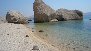 Ein Strand mit großen Felsen und klarem, flachem Wasser.