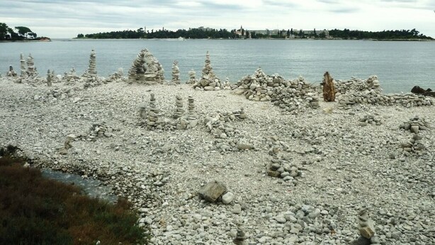 A rocky shoreline with stacks of stones and a calm body of water in the background. - Apartment in Rovinj with Balcony, Air condition, WIFI (230-1) (Rovinj)