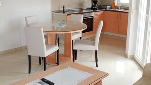 Une cuisine moderne avec des meubles de rangement orange, une table à manger avec des chaises et une machine à café.
