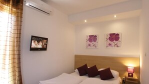 A hotel room with a bed, a nightstand with a lamp, and two wall-mounted flower paintings. - Studio apartment in Vodice with Terrace, Air condition, WIFI (4323-4) (Vodice)