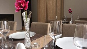 A dining table set with clear glassware and plates, a tall vase with pink flowers, and a candle. - Studio apartment in Vodice with Terrace, Air condition, WIFI (4323-4) (Vodice)