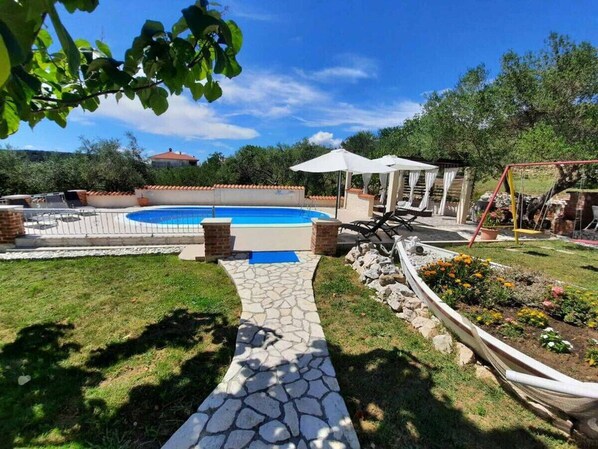 A backyard with a swimming pool, a stone pathway, a garden, and outdoor furniture. - Apartment in Kampor with Terrace, WIFI (4235-4) (Kampor)