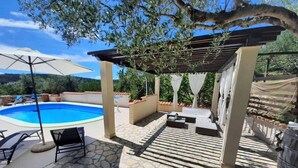 A poolside area with a pergola, lounge chairs, and a stone deck.