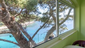 A room with a large window overlooking a clear blue body of water, surrounded by trees. - Apartment in Karbuni with Seaview, Balcony, Air condition (217-2) (Karbuni)