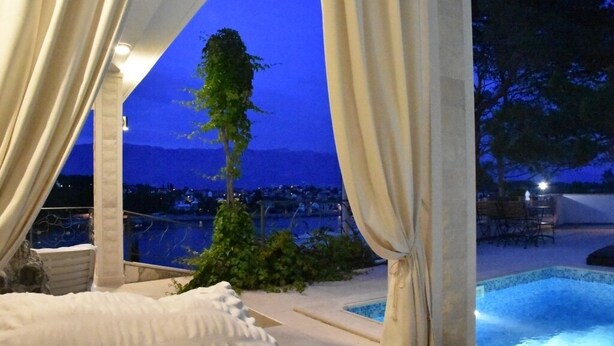 A bedroom with a view of a pool and mountains at dusk. - Holiday Home in Sumartin with Seaview, Air condition, WIFI, Washing machine (682-2) (Sumartin)