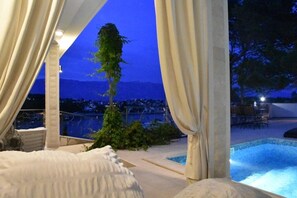 Camera da letto con vista su piscina e montagne al crepuscolo.