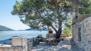 A stone-walled outdoor seating area with a stone barbecue and a view of the sea. - Apartment in Karbuni with Seaview, Terrace, Air condition, WIFI (217-3) (Karbuni)