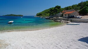 A beach with clear turquoise water, a small stone building, and boats. - Apartment in Karbuni with Seaview, Terrace, Air condition, WIFI (217-3) (Karbuni)