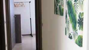 Un corridoio con pavimento in legno, una porta a sinistra e un muro decorato con motivi a foglia verde.