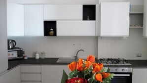 Una cucina moderna con mobili bianchi, piano cottura a gas, lavello e tostapane.