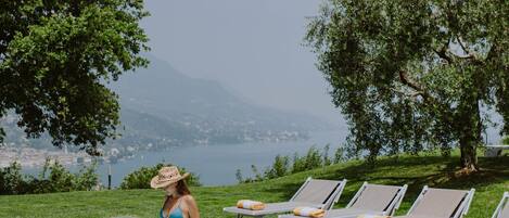 Une femme en bikini, près d’une piscine, avec des chaises longues et une vue sur les montagnes.