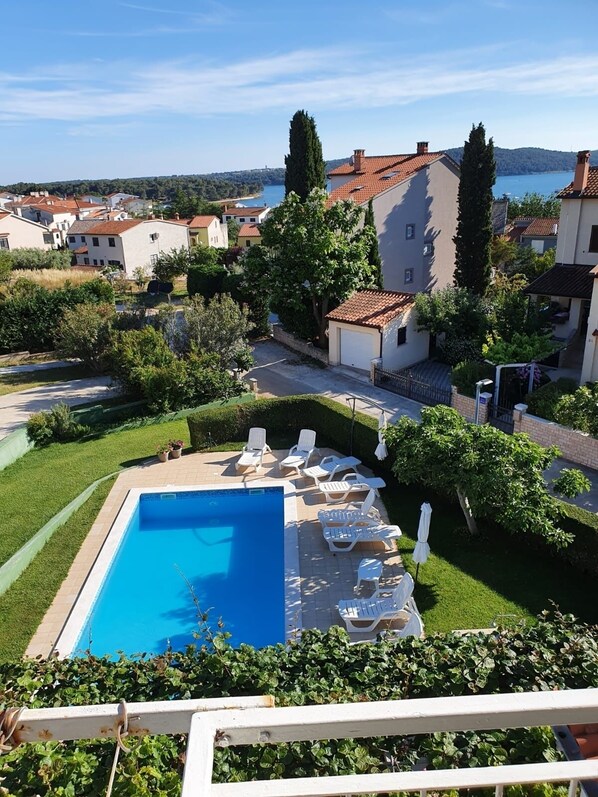 A swimming pool with lounge chairs and a view of a lake and buildings in the background. - Apartment in Medulin with Loggia, Air condition, WIFI (112-3) (Medulin)