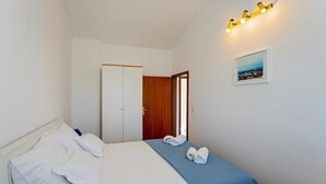 A hotel room with a bed, a wardrobe, a door, and a wall-mounted light fixture.